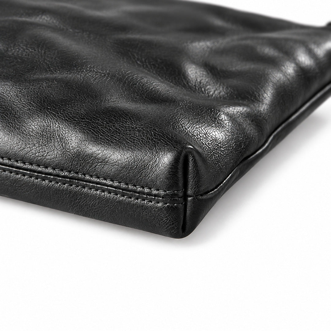 Close-up of a black leather pouch or clutch showing the textured grain and stitched edge.