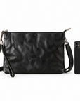A black leather clutch bag with a wristlet strap and silver-tone hardware, shown next to a black smartphone for scale.
