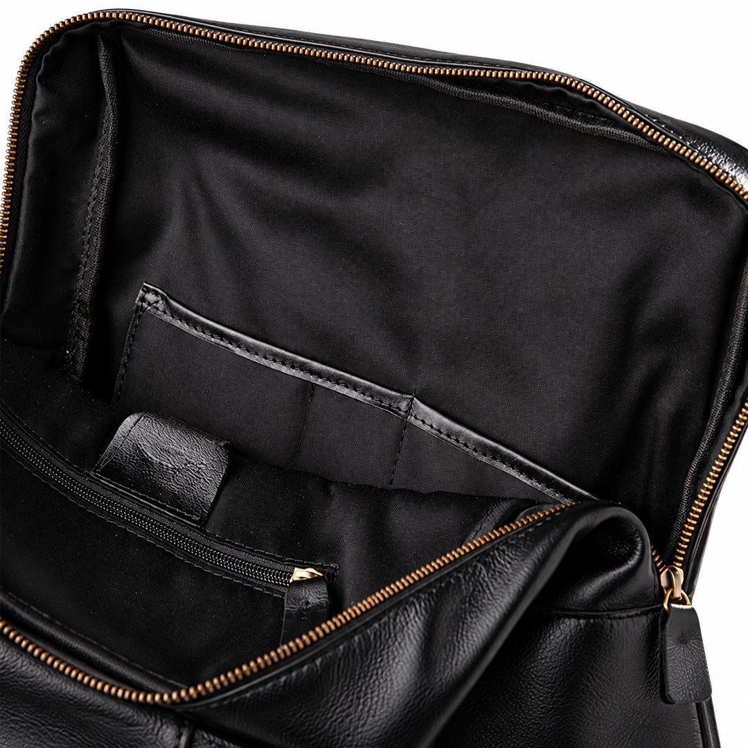 Close-up of the interior of a black leather bag, showing a spacious black fabric lining, a zippered pocket, and gold-tone zipper hardware.