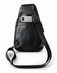 Rear view of a black leather sling bag with a silver smartphone partially inserted into the back slip pocket.