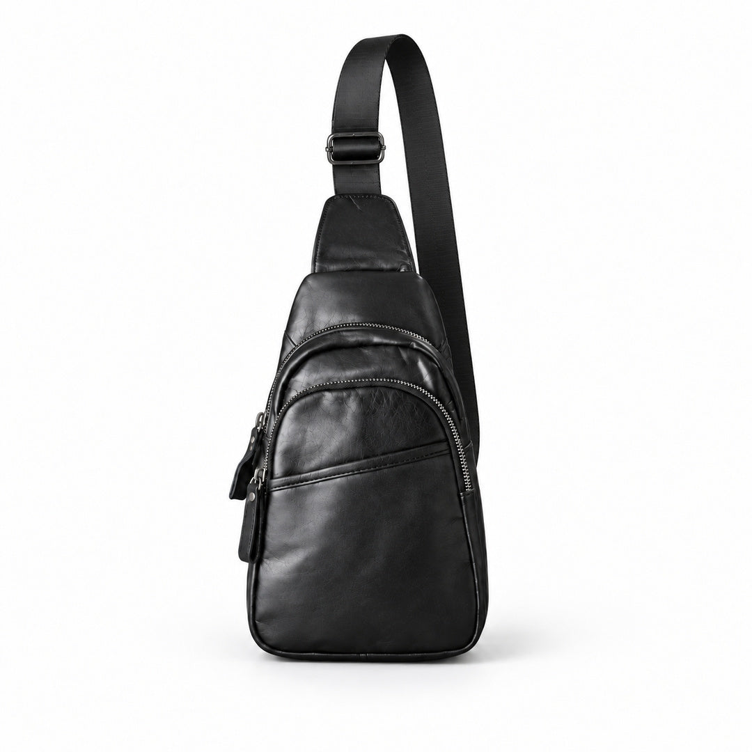 Front view of a black leather double-zip sling bag with its entire adjustable shoulder strap visible against a white background.