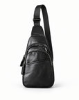 Front view of a black leather double-zip sling bag with its entire adjustable shoulder strap visible against a white background.