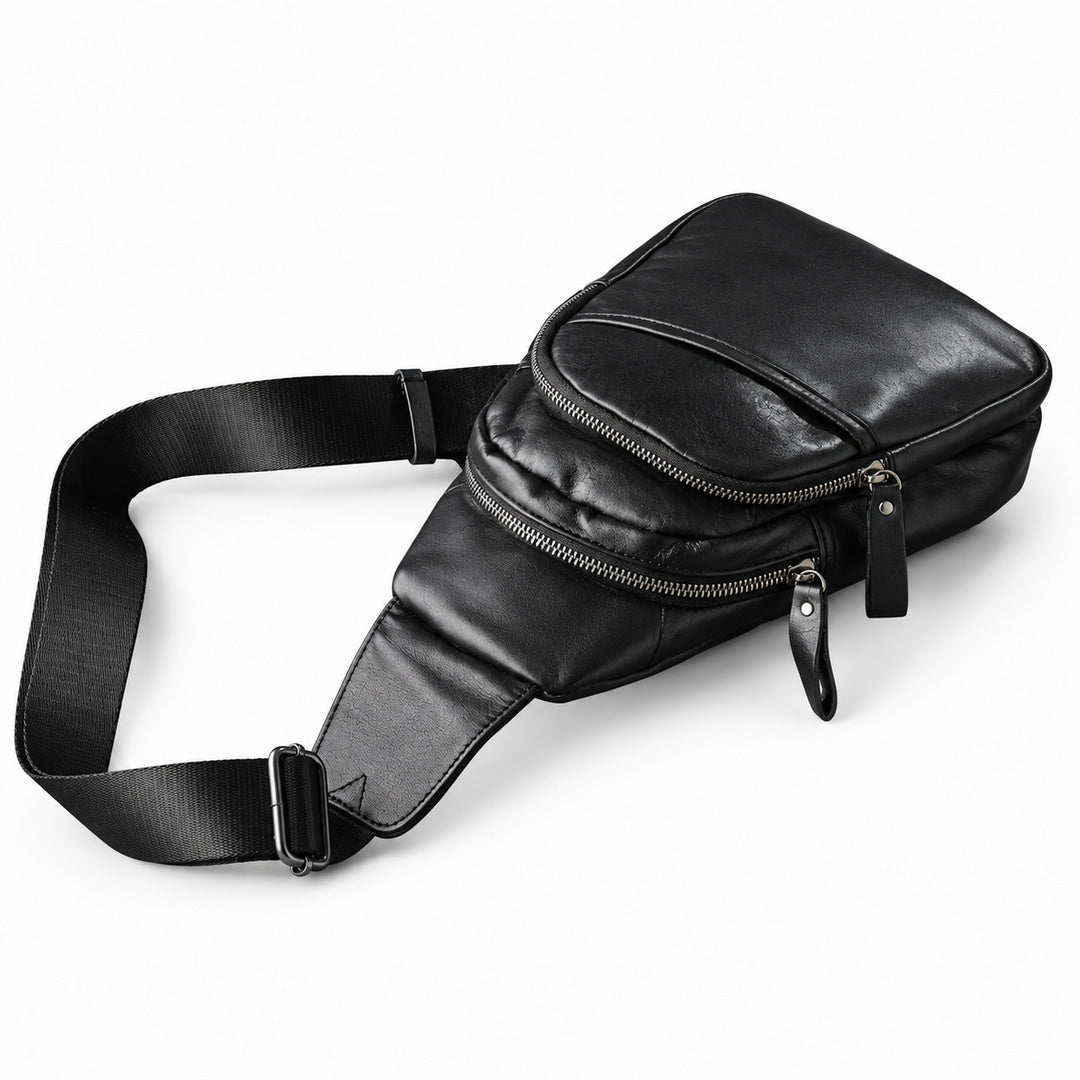 Side view of a black leather sling bag showing two separate zip compartments and the shoulder strap.