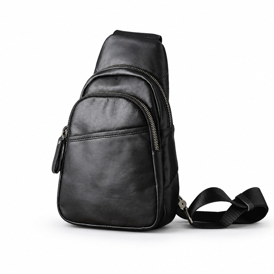 Black leather sling bag with two curved zip compartments and a front slip pocket, shown at a slight angle.
