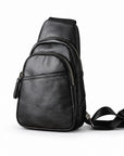 Black leather sling bag with two curved zip compartments and a front slip pocket, shown at a slight angle.