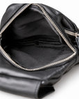 Black leather crossbody bag shown open to display the interior, featuring silver-tone metal zippers and a black fabric lining.