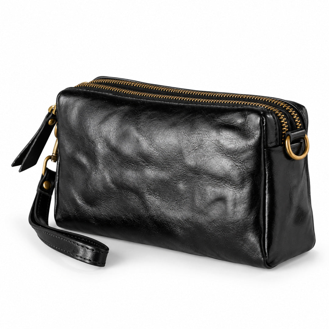 Black leather crossbody pouch with gold-tone hardware and a wrist strap, shown.