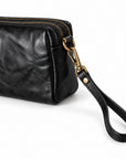 A close-up of a black leather wristlet clutch with a top zipper, gold-tone hardware, and a matching black leather wrist strap.