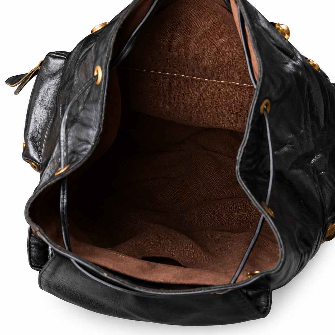 Close-up of the interior of a black leather handbag with a brown fabric lining and gold-tone hardware, shown against a white background.
