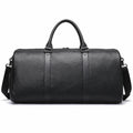A black textured leather duffel bag with dual top handles and a detachable shoulder strap, shown against a plain white background.