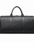 A black textured leather duffel bag with dual top handles and a detachable shoulder strap, shown against a plain white background.