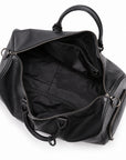 A black pebbled leather duffel bag shown open from an overhead angle, revealing a black fabric interior with zippered compartments and dual top handles on a white background.