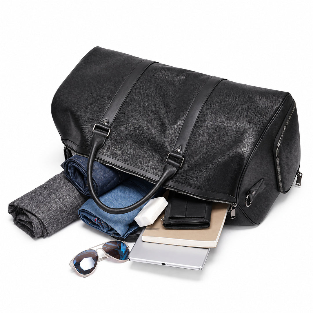 A black leather duffel bag shown open on a white background, with folded clothing, a wallet, a tablet, and sunglasses placed inside and around it.