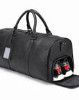 A black pebbled leather duffel bag with dual top handles, a luggage tag, and an open side compartment showing two red and white beverage cans inside, set against a plain white background.