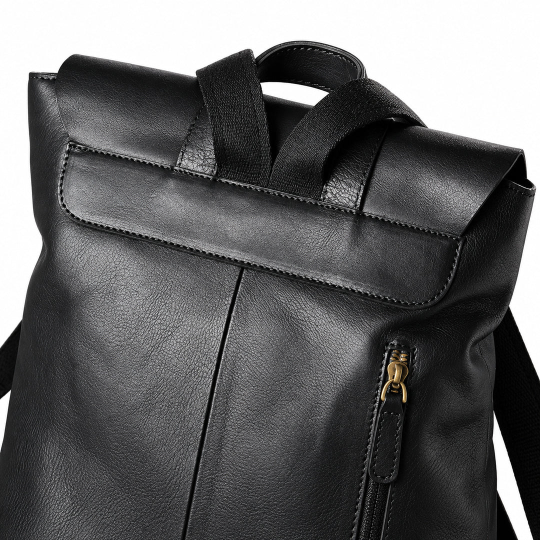 Close-up of a black faux-leather backpack showing the top flap, dual top handles, and a gold-tone zipper.