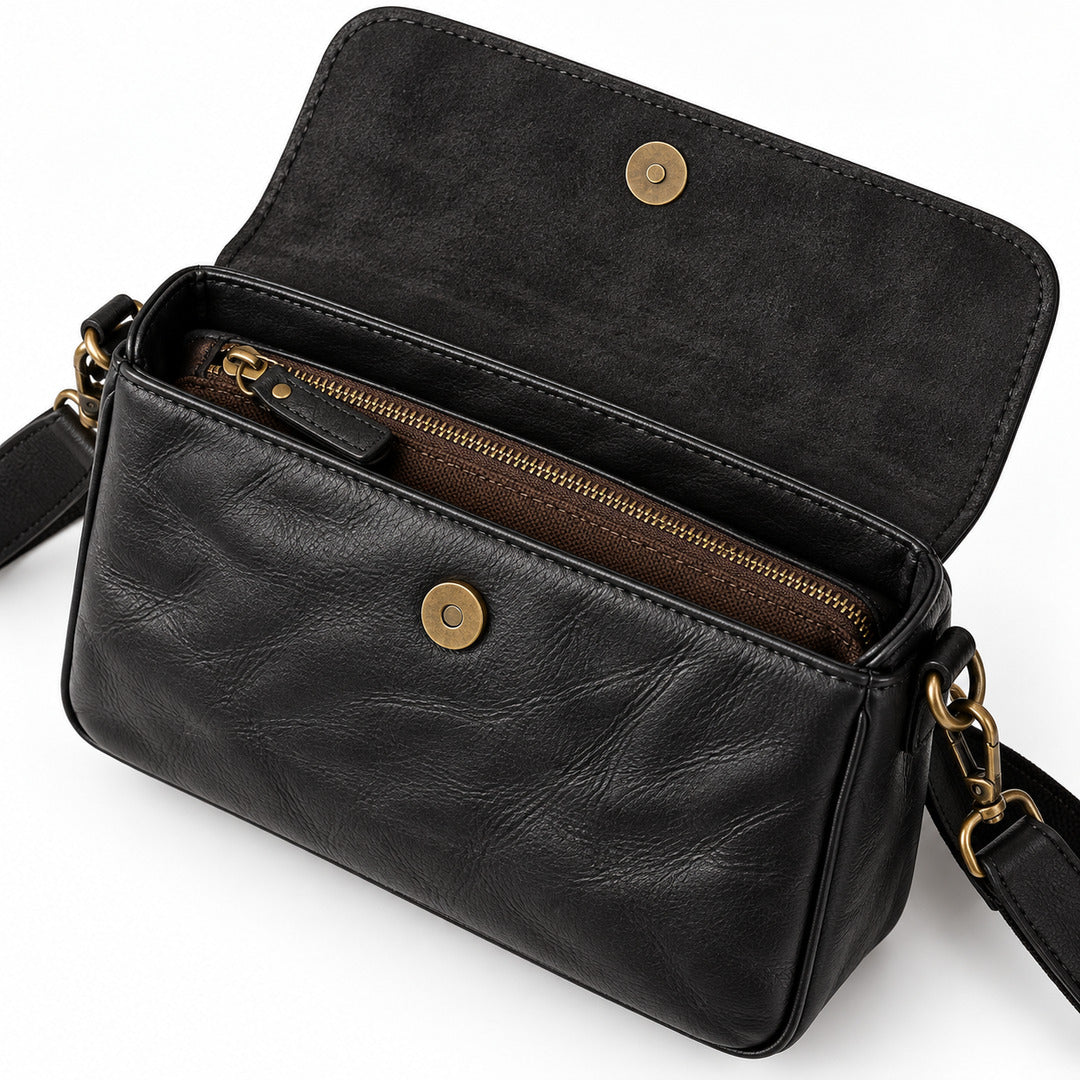 Black leather crossbody handbag with an open flap, showing a brown interior zippered pocket and gold-tone hardware.
