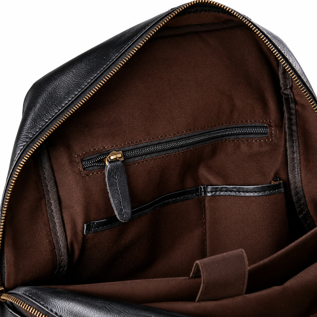 Close-up of the interior of a black leather bag showing a brown fabric lining with a zippered pocket and gold-tone zipper hardware.