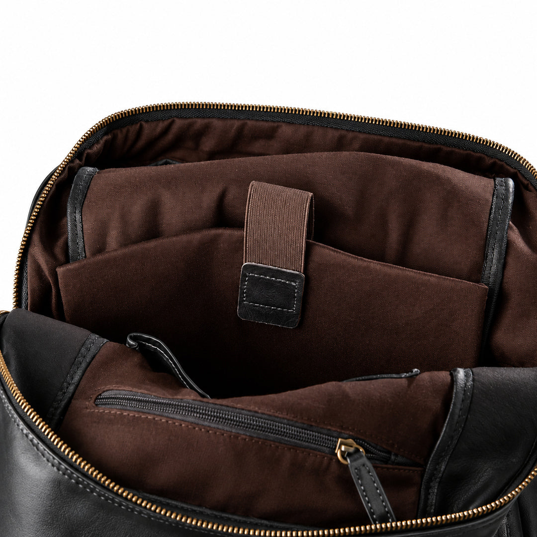 Close-up of the interior of a dark brown and black leather bag, showing a brown fabric organizer pocket with an elastic strap and a zippered compartment.