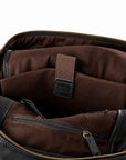 Close-up of the interior of a dark brown and black leather bag, showing a brown fabric organizer pocket with an elastic strap and a zippered compartment.