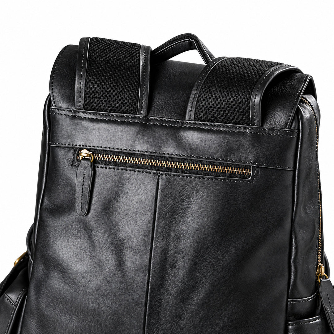 Close-up of a black leather backpack showing the front pocket with a gold zipper, padded shoulder straps, and mesh side panels.