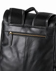 Close-up of a black leather backpack showing the front pocket with a gold zipper, padded shoulder straps, and mesh side panels.