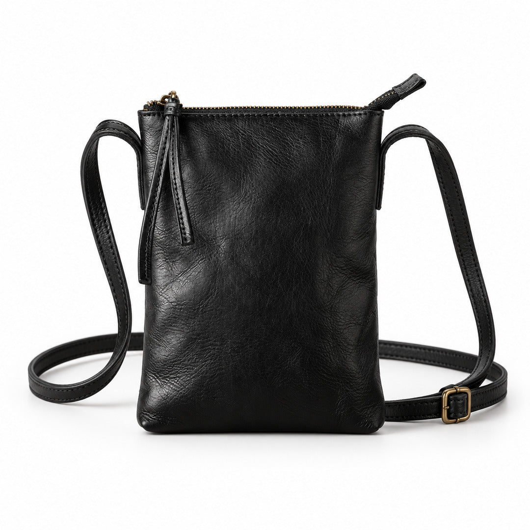 Black leather crossbody bag with a top zipper, front zipper pocket, and adjustable shoulder strap on a white background.