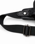 Close-up of the sling bag's black woven shoulder strap, metal adjustment buckle and leather snap attachment.