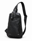 Angled view of a black leather sling bag showing its tapered shape and adjustable shoulder strap.