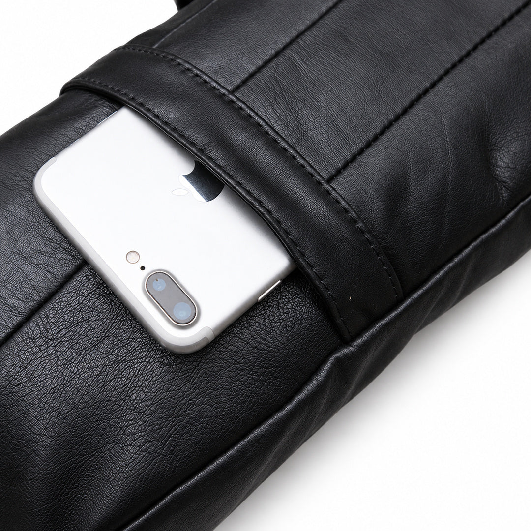 Close-up of a silver smartphone partially tucked into the black leather sling bag's rear slip pocket.