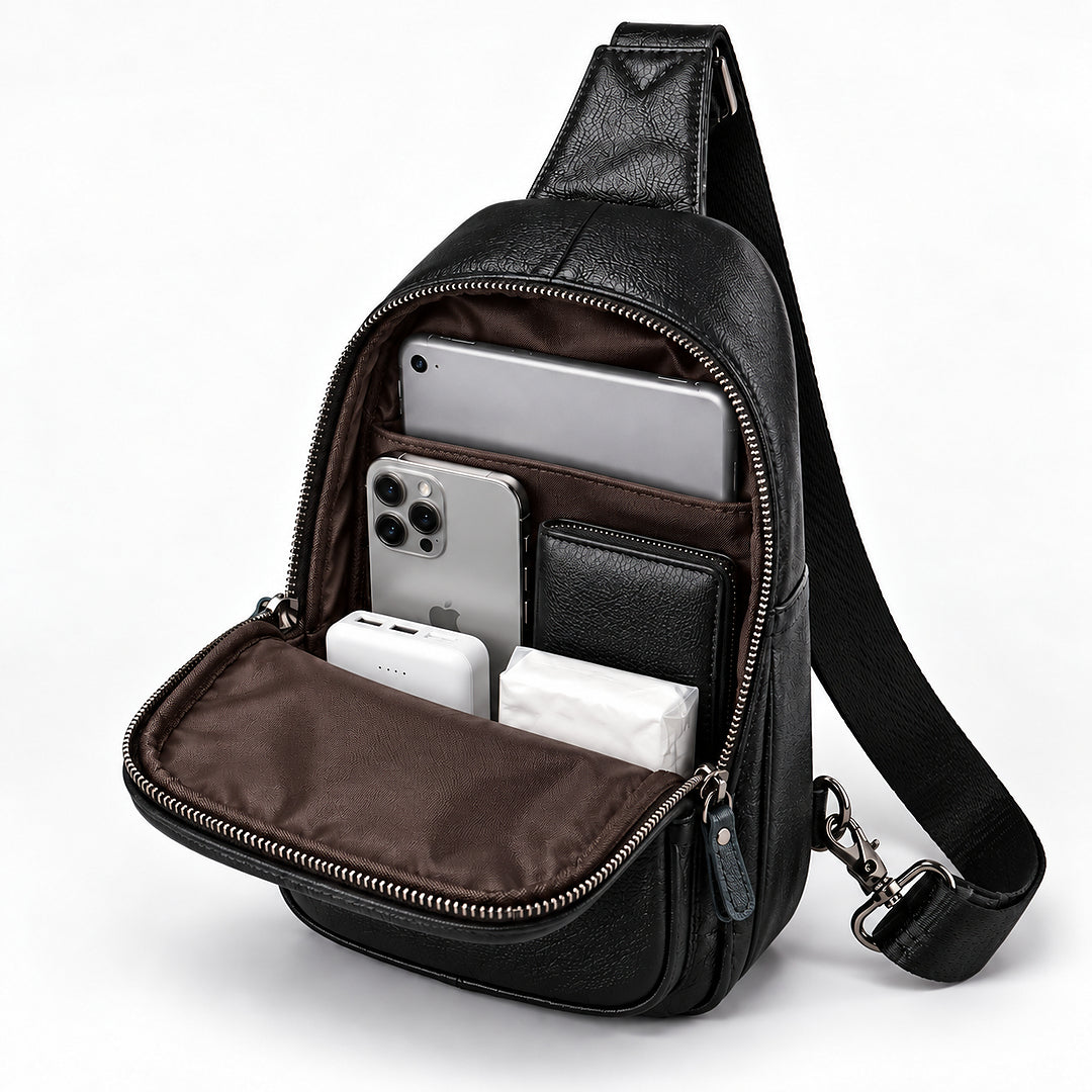 Black leather crossbody bag with an open front pocket showing a brown interior, filled with a smartphone, wallet, earbud case, and tissue. The bag has a black shoulder strap and silver-tone zippers, photographed on a clean white background.