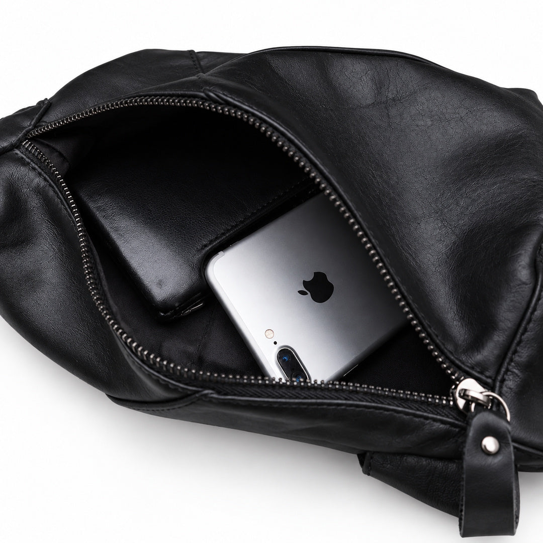 Open main compartment of a black leather sling bag holding a smartphone and black wallet.