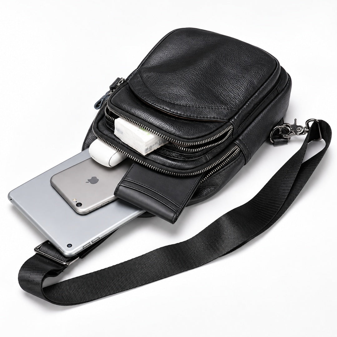 Black leather crossbody phone bag with a zippered front pocket, shown with a smartphone, earbuds, and a strap on a white background.