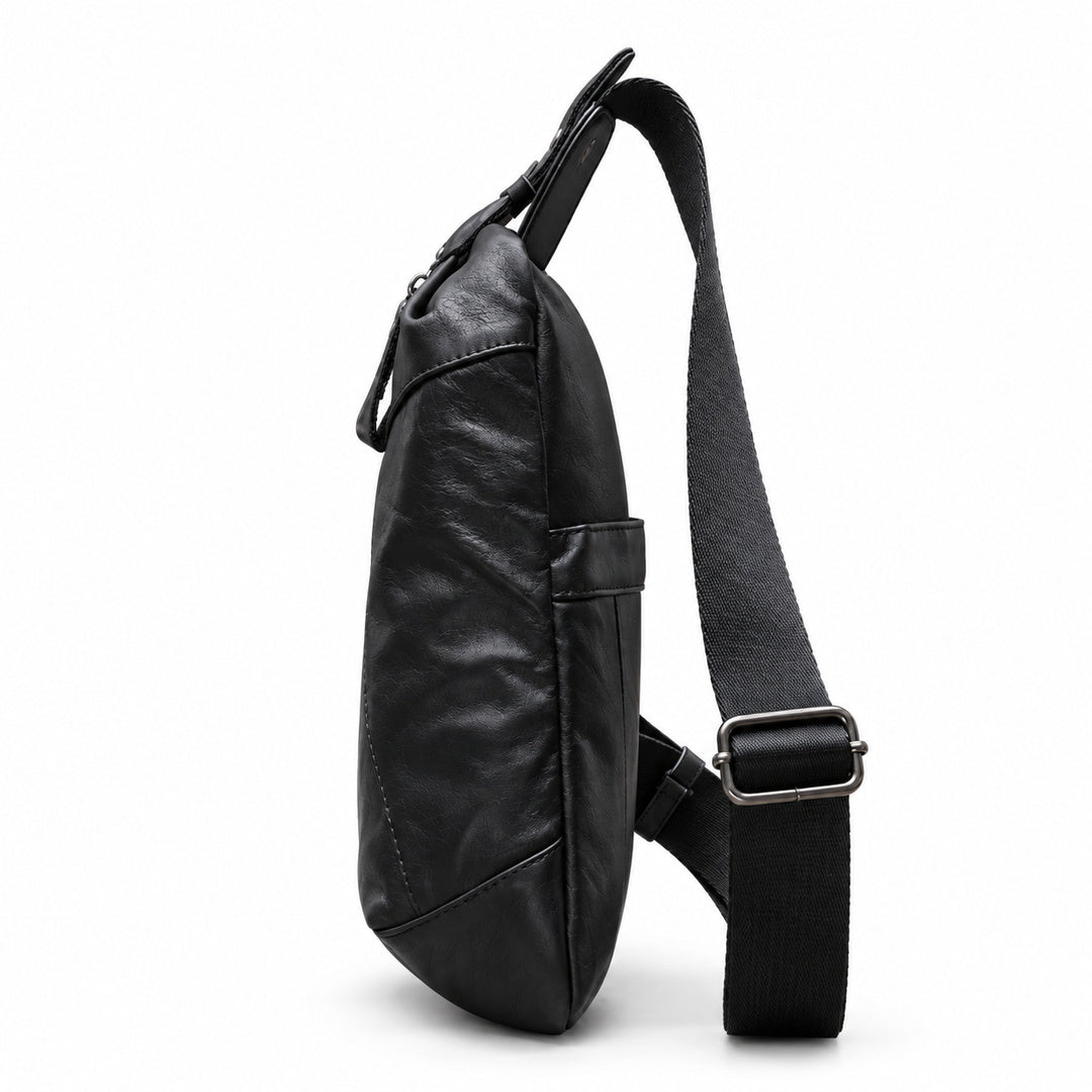 Side view of a black leather sling bag showing its slim profile and metal strap adjuster.