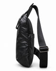 Side view of a black leather sling bag showing its slim profile and metal strap adjuster.