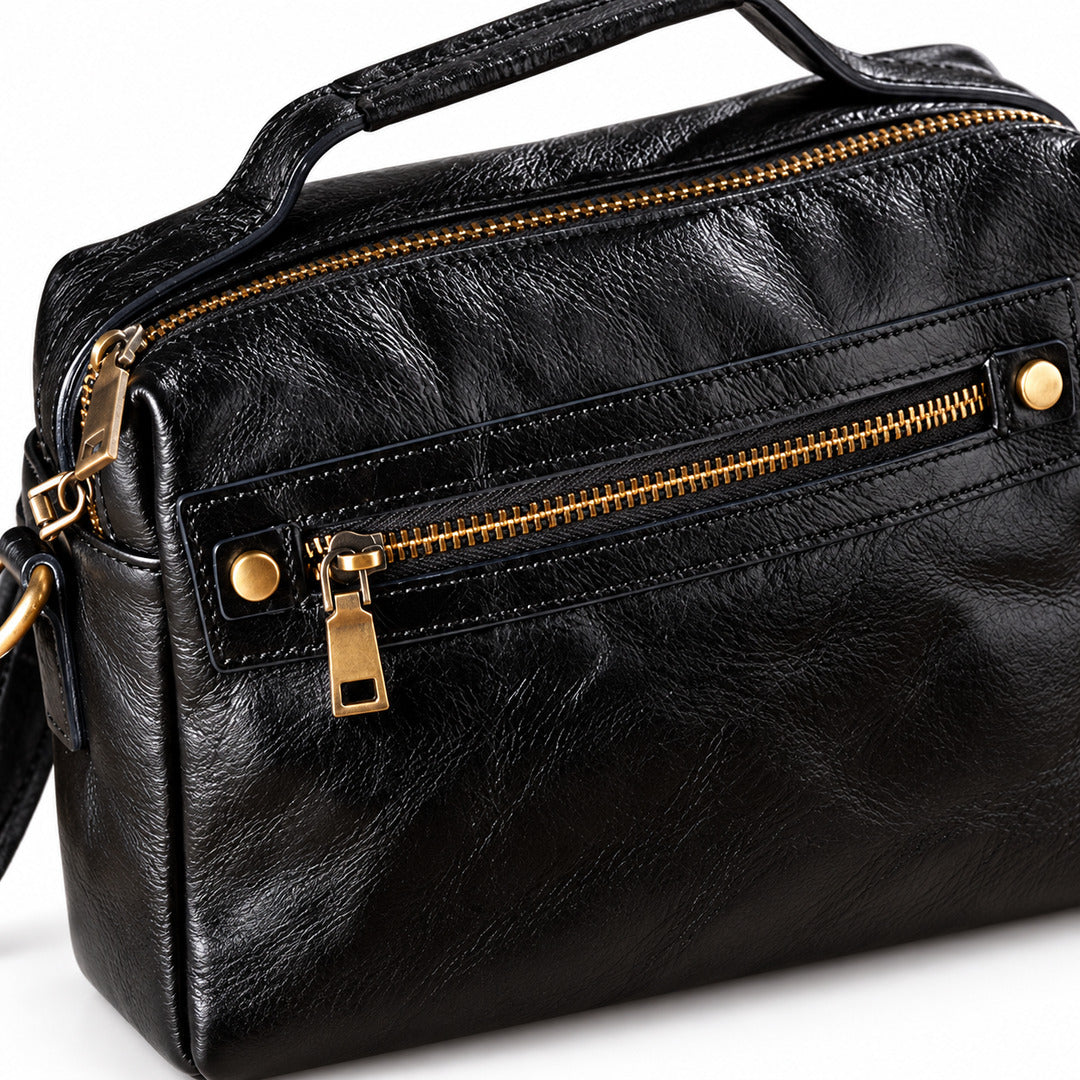Black textured leather handbag with gold-tone zippers and hardware.