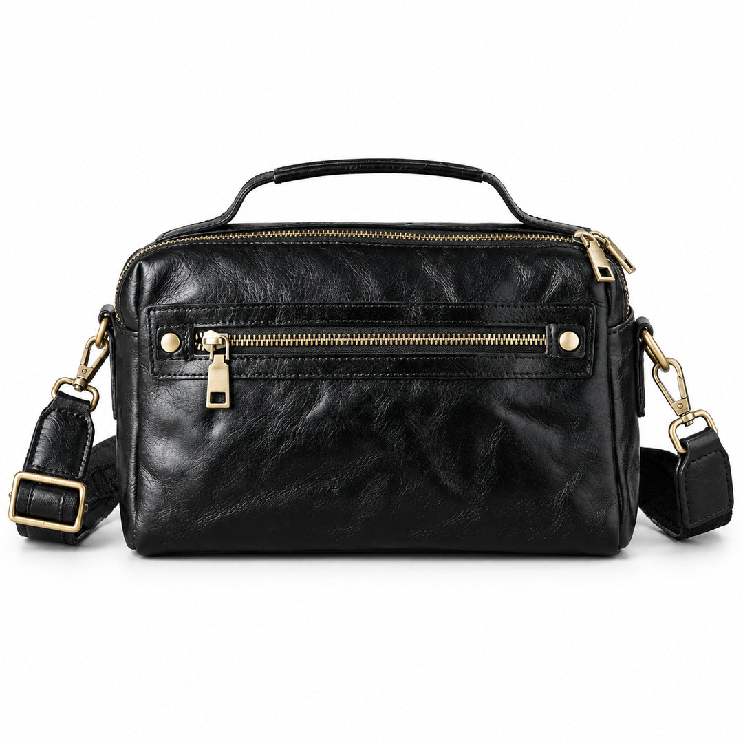 Black leather crossbody handbag with gold-tone hardware, featuring a top handle, a front zip pocket, and an adjustable shoulder strap.