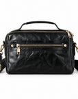 Black leather crossbody handbag with gold-tone hardware, featuring a top handle, a front zip pocket, and an adjustable shoulder strap.