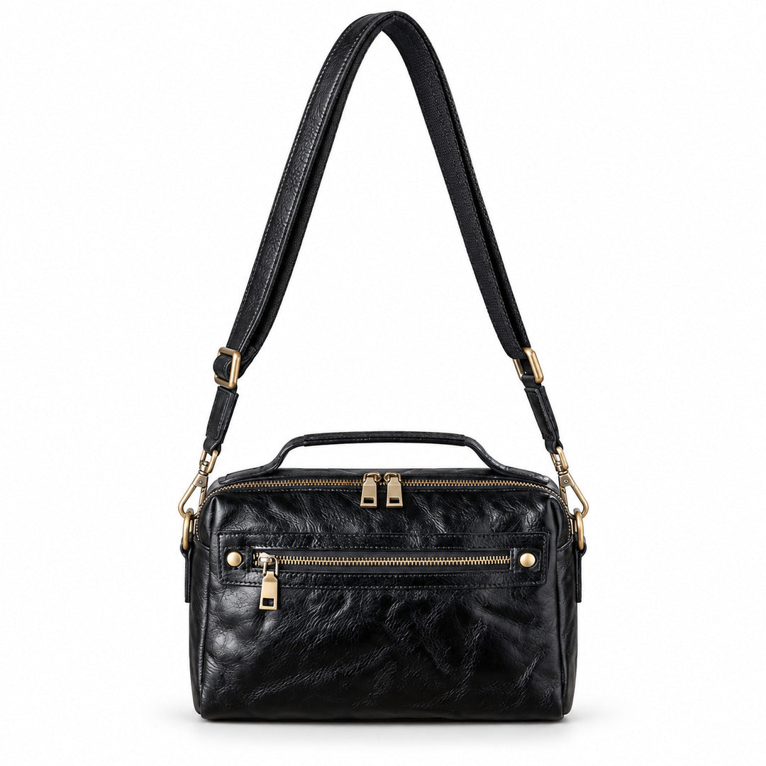 Black leather crossbody bag with gold-tone hardware, featuring a top handle, a shoulder strap, and multiple zippered compartments.