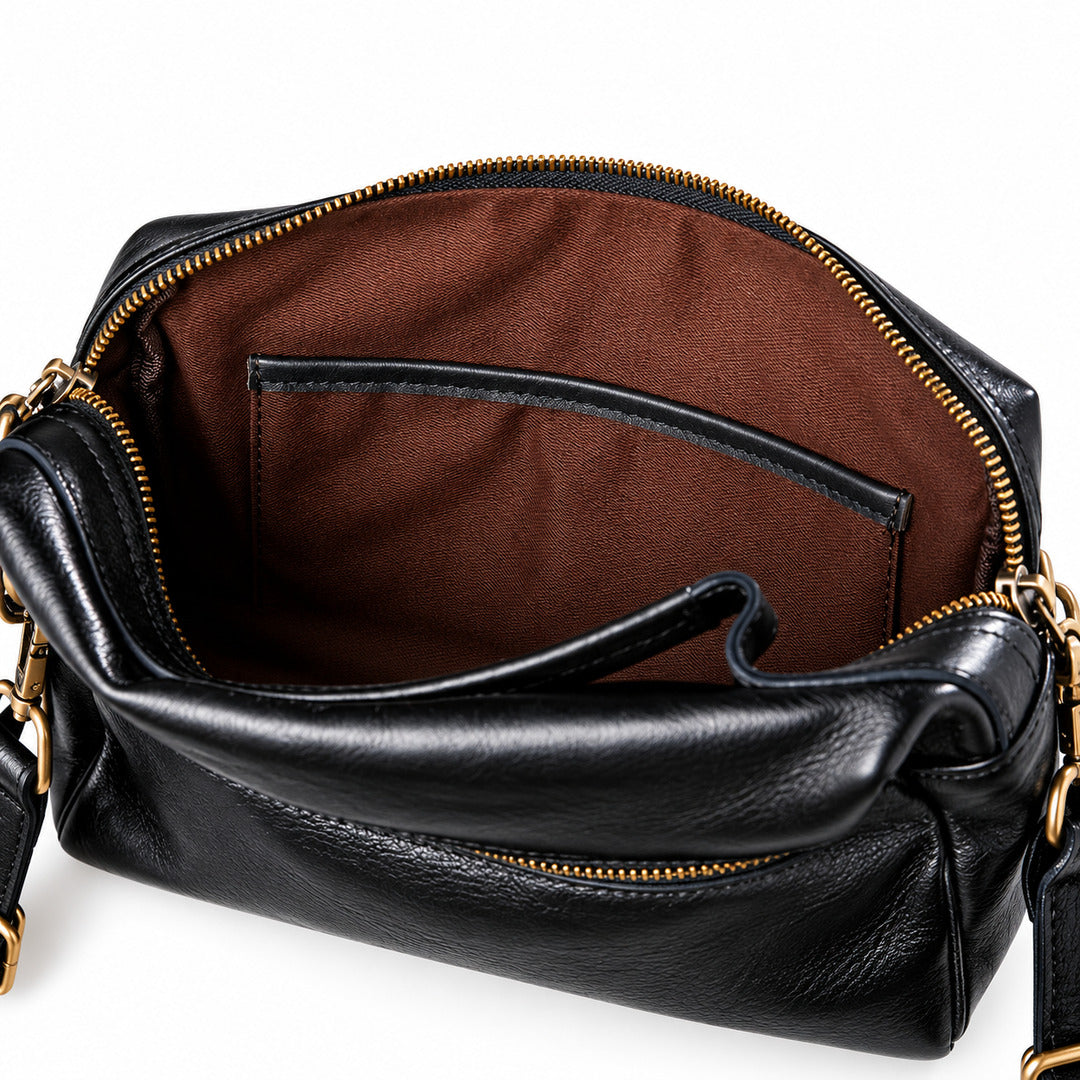 Black pebbled leather handbag shown open to reveal a brown fabric interior with a zip-around top and gold-tone hardware.