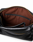 Black pebbled leather handbag shown open to reveal a brown fabric interior with a zip-around top and gold-tone hardware.
