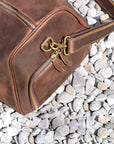 Close-up of brass zippers and details on the side pocket of a premium leather duffle bag.