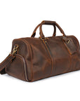 Side angle of a brown handcrafted leather weekender bag featuring premium brown leather and adjustable shoulder strap.