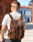 Man wearing a brown leather backpack in an urban setting