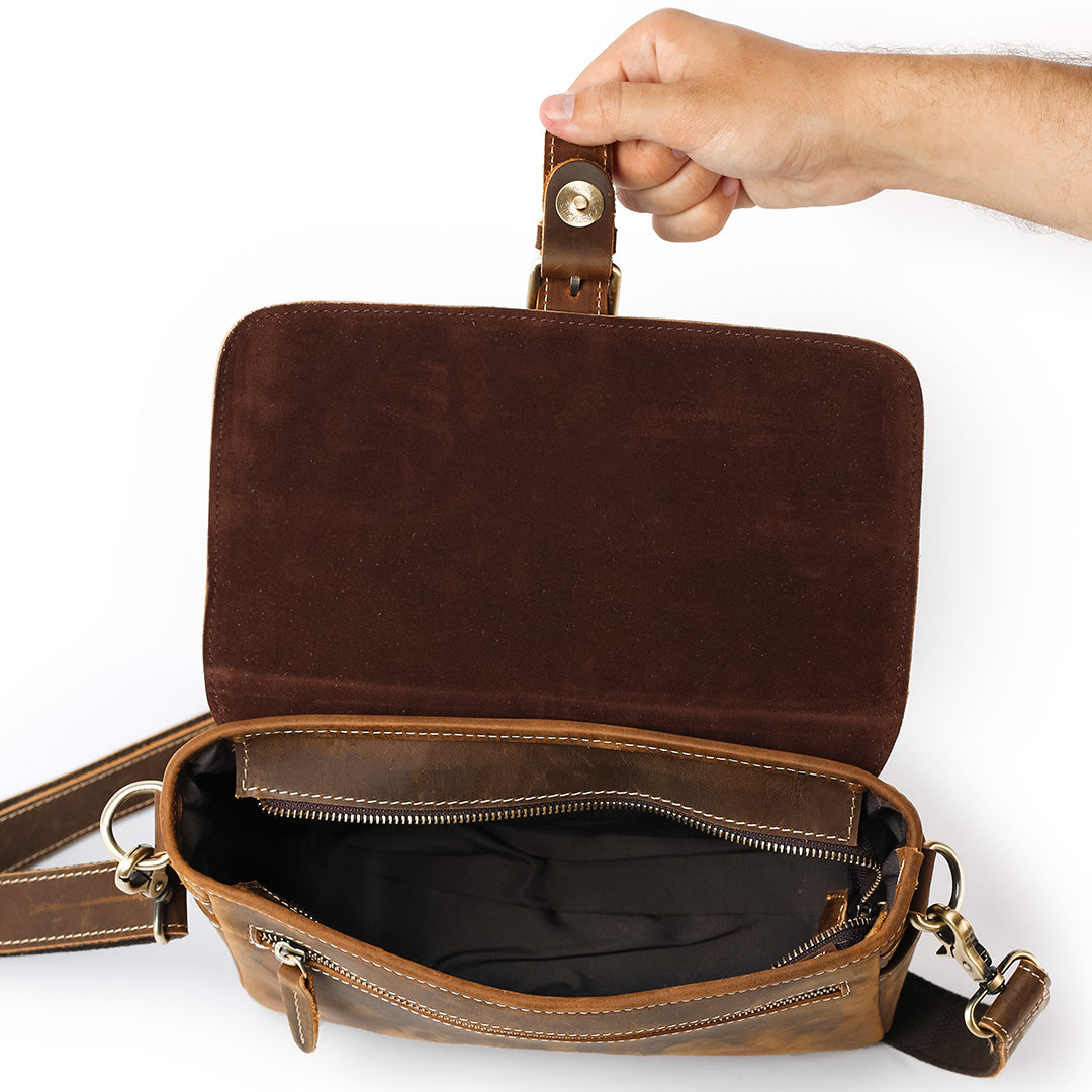 Brown leather bag with a hand holding its handle on a white background