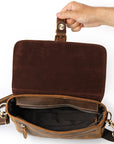 Brown leather bag with a hand holding its handle on a white background