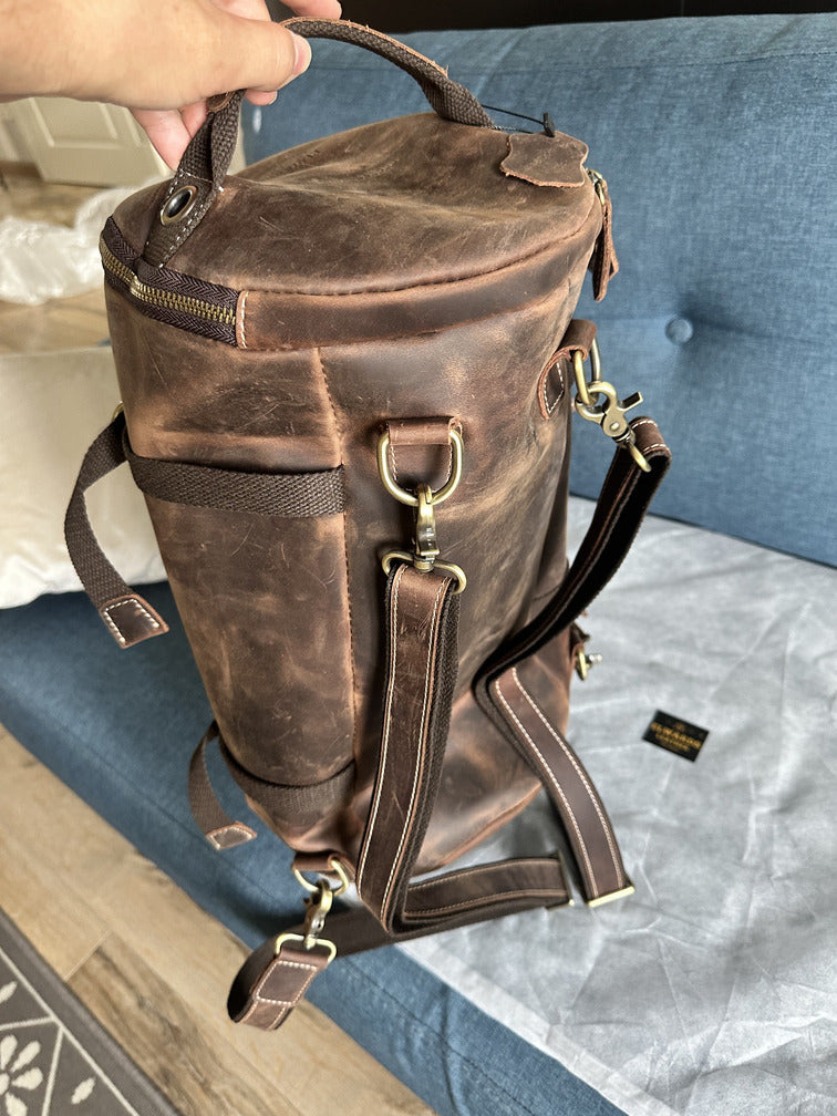 Customer showing the craftsmanship of a brown leather backpack with detailed stitching and vintage look