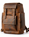 A brown distressed leather backpack with multiple front pockets, brass-tone hardware, and a top flap.