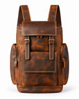 A brown distressed leather backpack with a front flap pocket, side pockets, and brass-tone hardware.