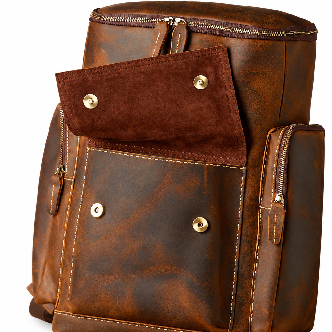 A brown distressed leather backpack with a front flap pocket featuring brass snap buttons and a main zippered compartment.