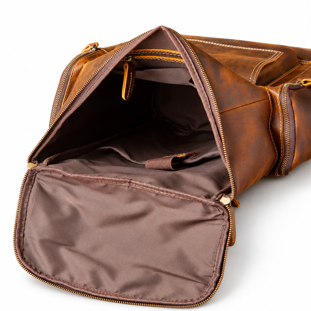 An open brown leather bag with gold-tone zippers, showing a dark brown interior lining and organized compartments.